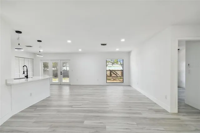 a view of an empty room with window and wooden floor