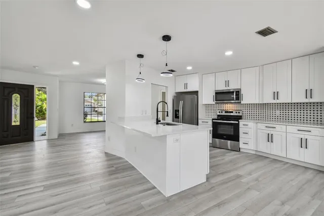 a large kitchen with stainless steel appliances kitchen island granite countertop a stove and a sink