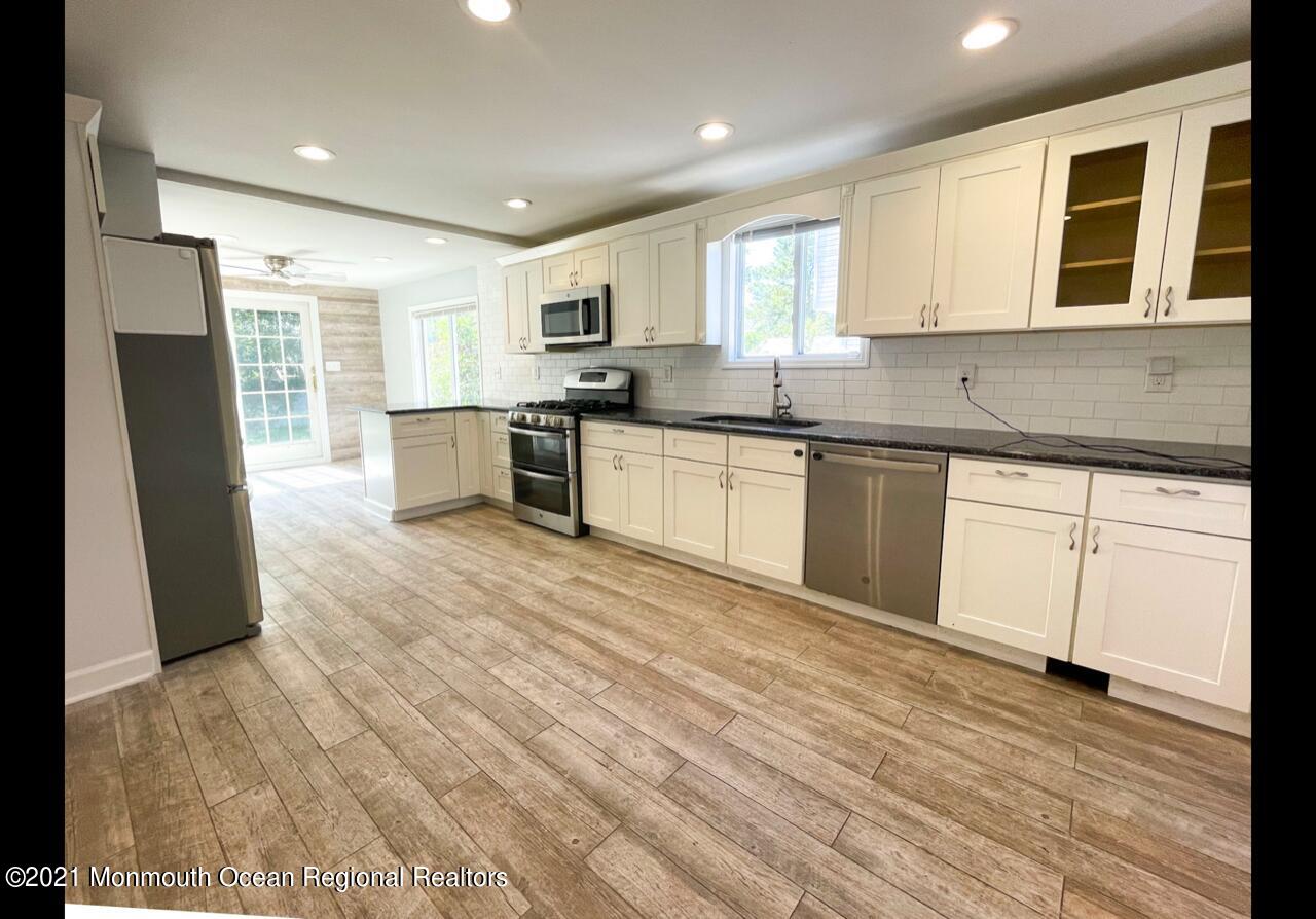 330 Front Street Union Beach, NJ 07735 - Photo 7 of 23 a large kitchen with stainless steel appliances granite countertop a stove a sink dishwasher and a refrigerator with wooden floor