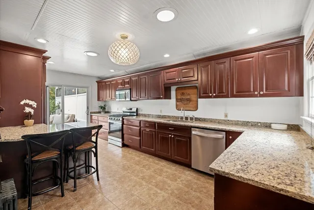 a kitchen with stainless steel appliances granite countertop wooden cabinets a stove and a sink