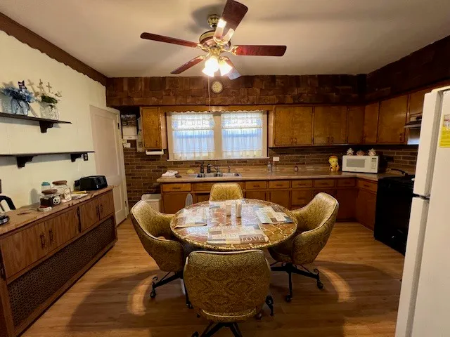 a kitchen with stainless steel appliances granite countertop a sink a stove a dining table and chairs with wooden floor