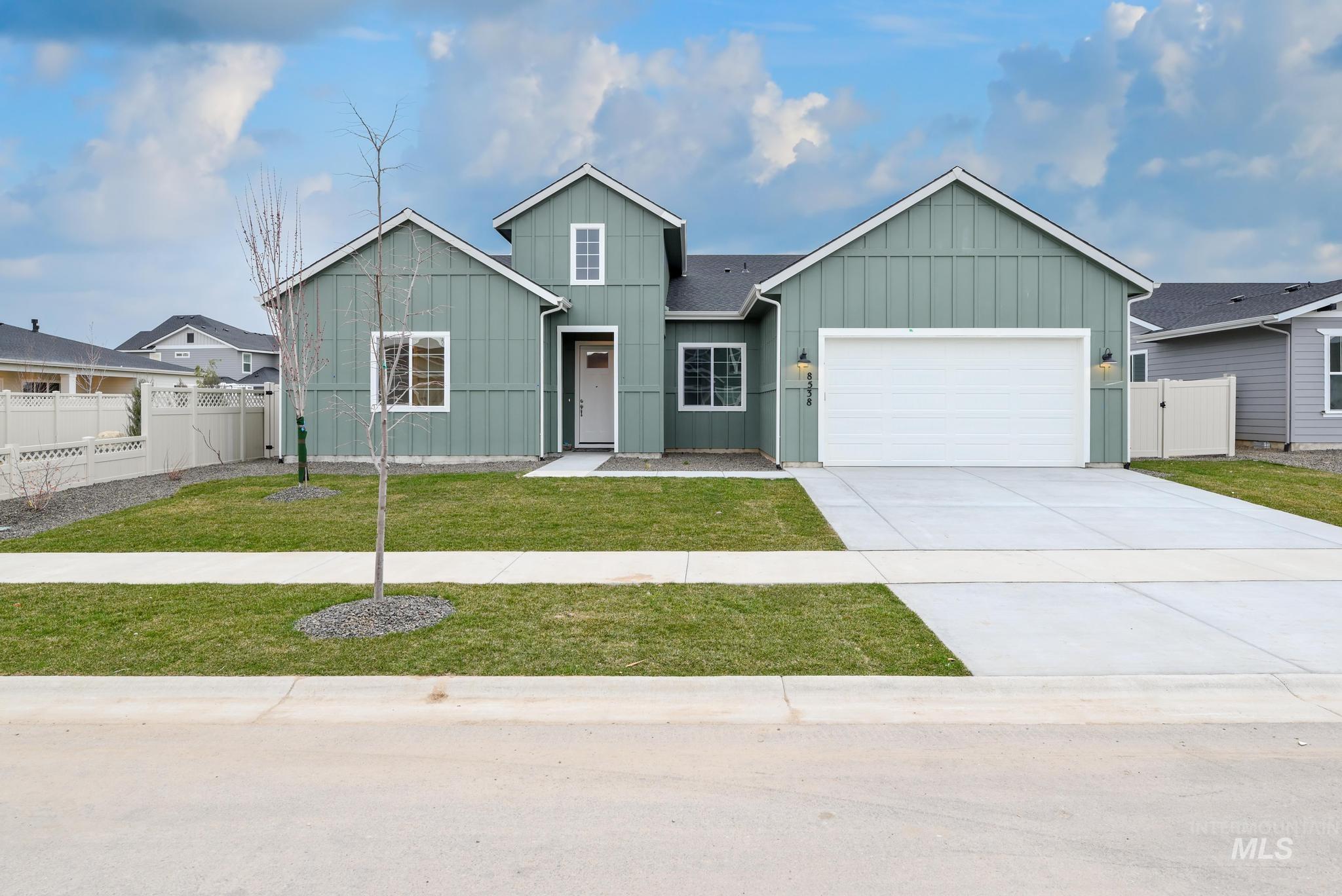 View of front of home featuring board and batten siding, a gate, a garage, and driveway