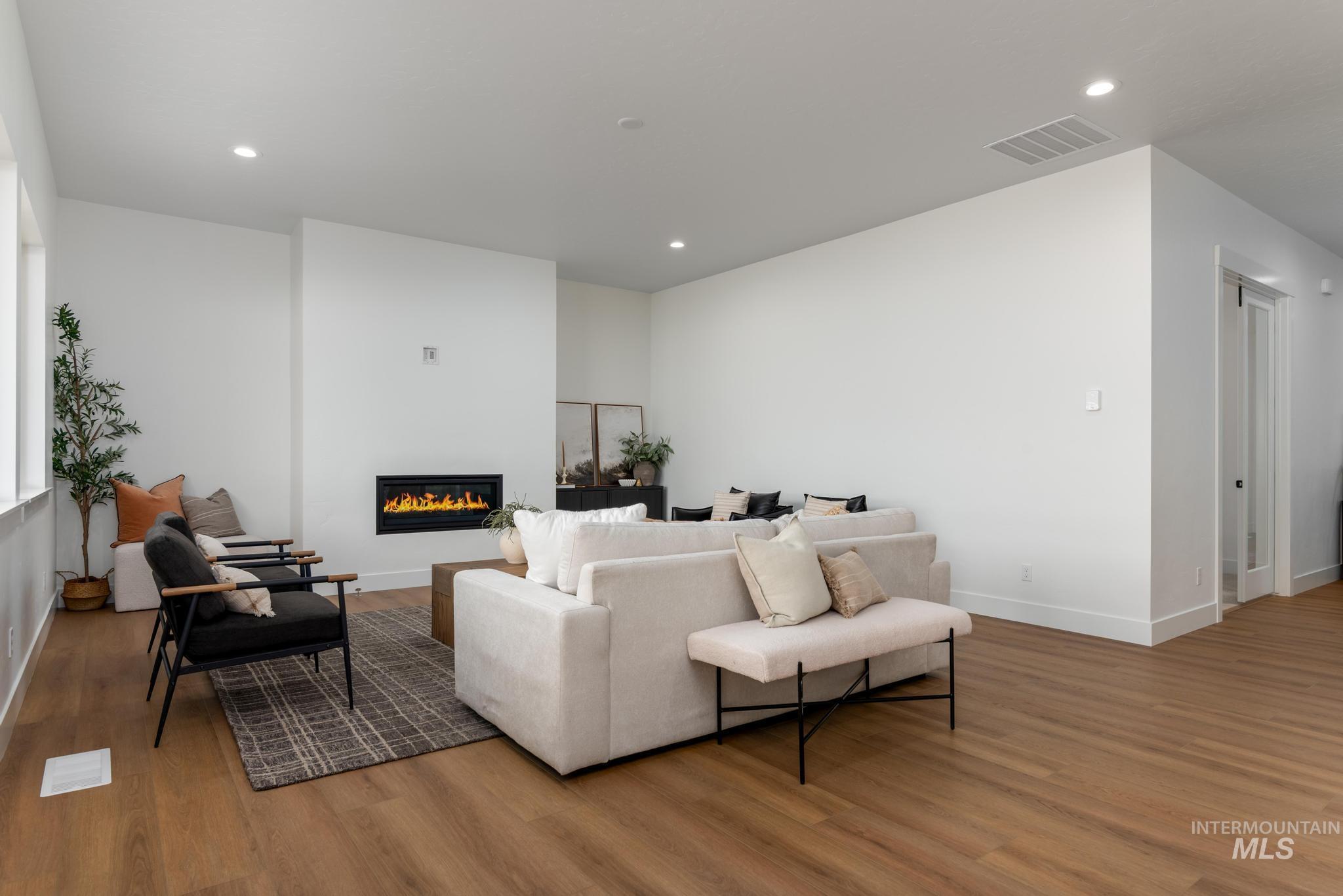 8558 South Silver Smog Way Meridian, ID 83642 - Photo 2 of 13 Living room featuring wood finished floors, recessed lighting, and a glass covered fireplace