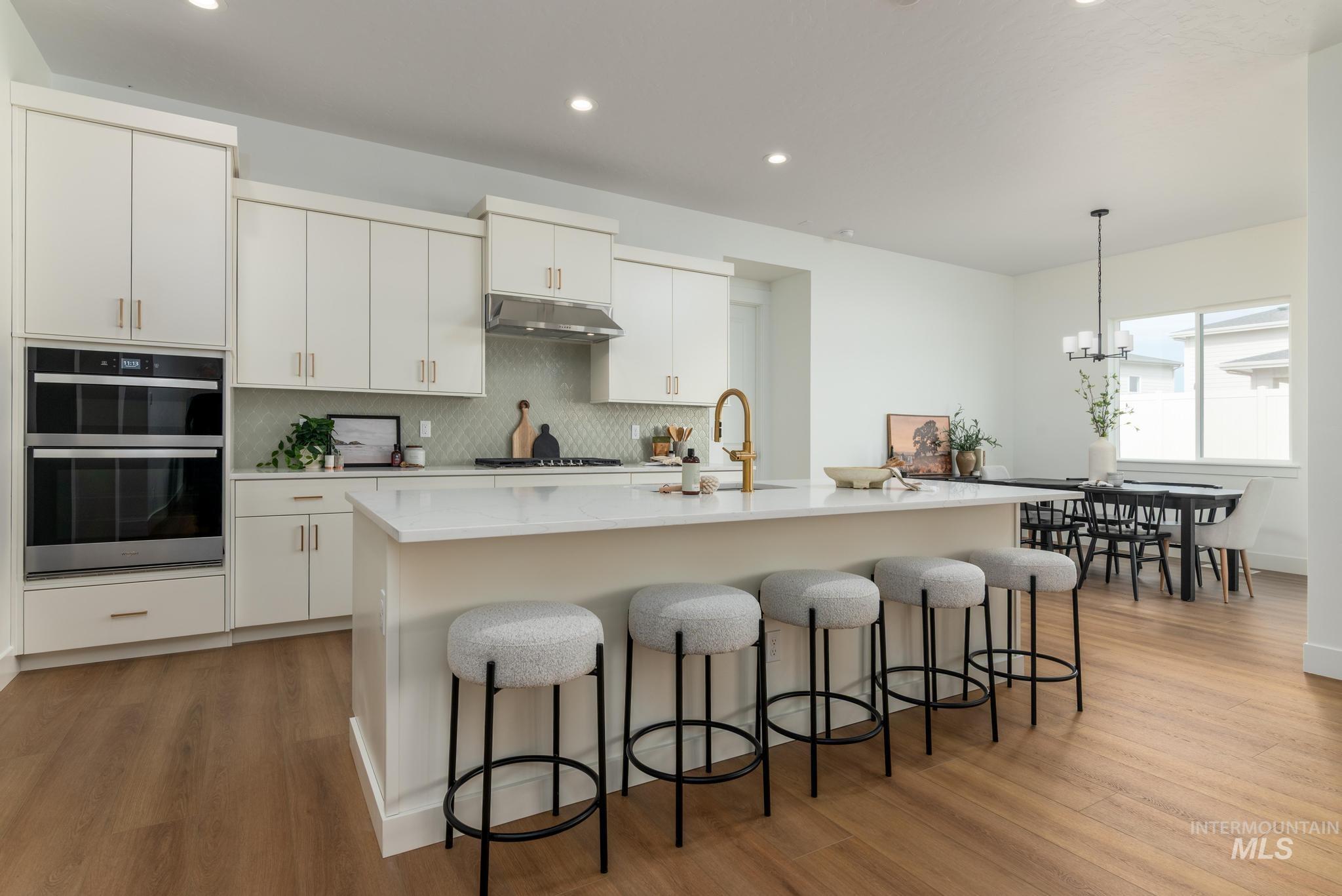 8558 South Silver Smog Way Meridian, ID 83642 - Photo 4 of 13 Kitchen with light wood-style flooring, double oven, a kitchen bar, and a kitchen island with sink