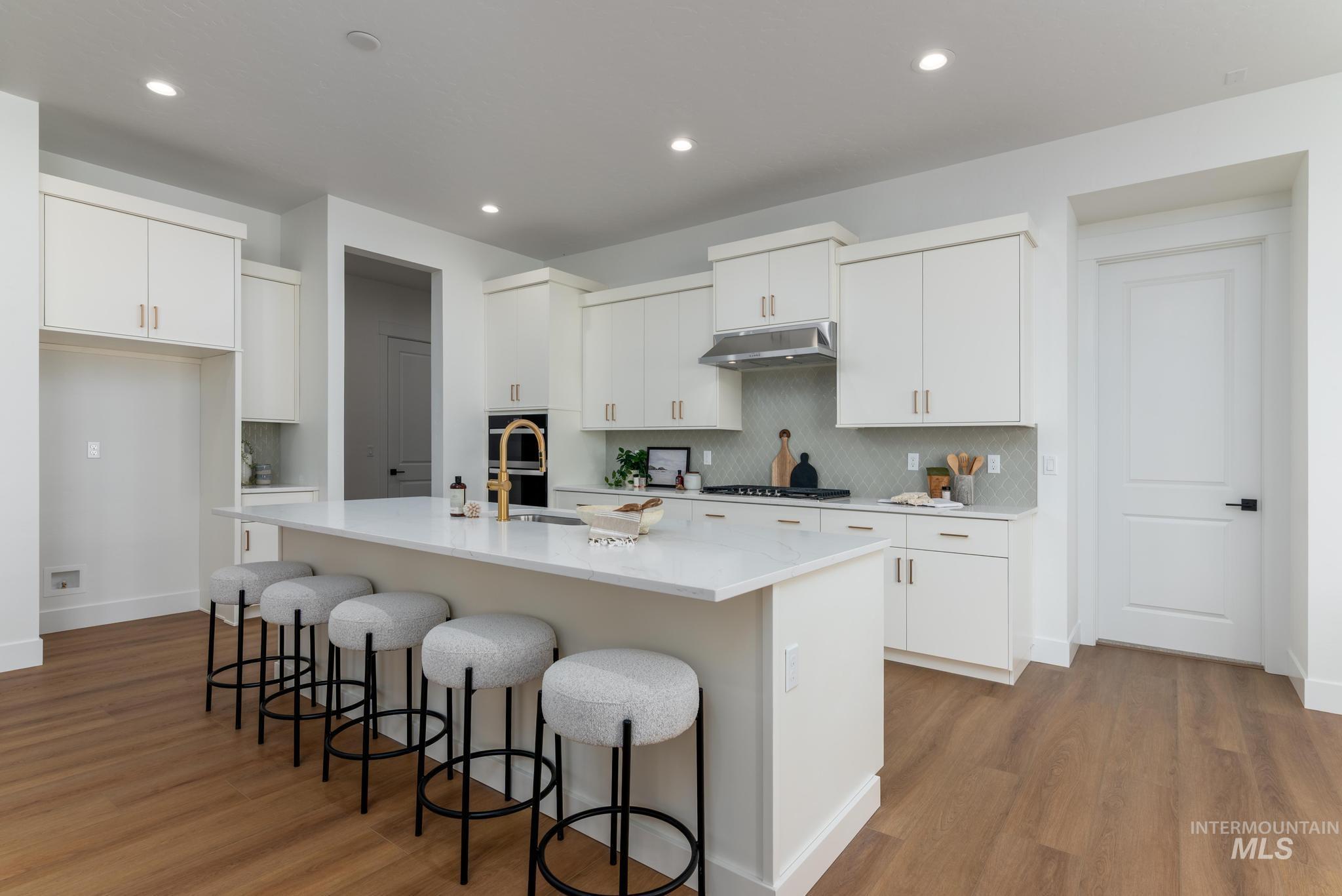 8558 South Silver Smog Way Meridian, ID 83642 - Photo 5 of 13 Kitchen with white cabinetry, a breakfast bar area, dark wood finished floors, tasteful backsplash, and a kitchen island with sink