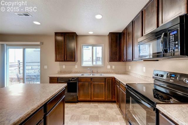 944 Diamond Rim Drive Colorado Springs, CO 80921 - Photo 10 of 28 Breakfast bar/Island with convenient storage. Walkout and over the sink window add natural lighting to this highly functional kitchen.