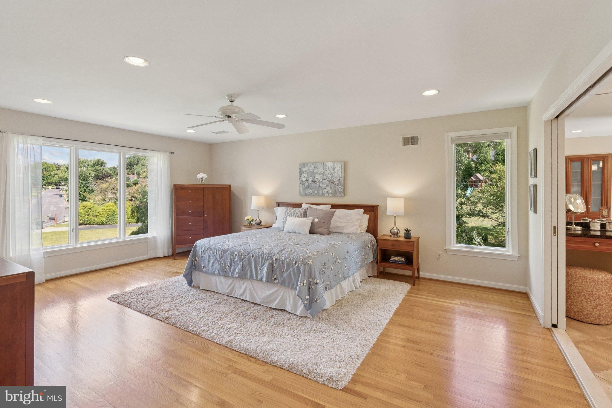 9817 Conestoga Way Potomac, MD 20854 - Photo 18 of 35 a spacious bedroom with a large bed a chandelier and windows