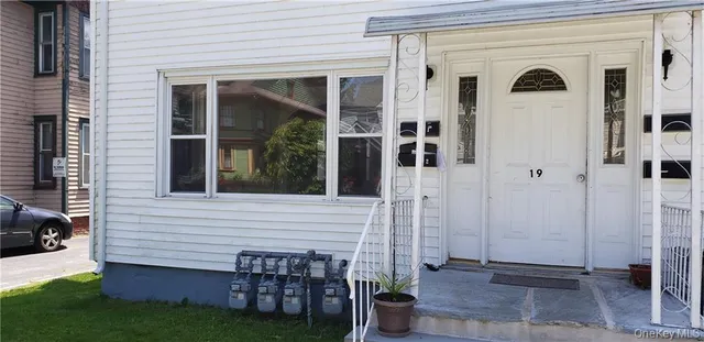 a view of a porch with chairs and potted plants next to a yard