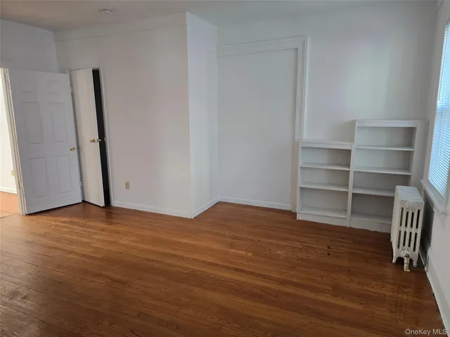 a view of empty room with wooden floor and closet