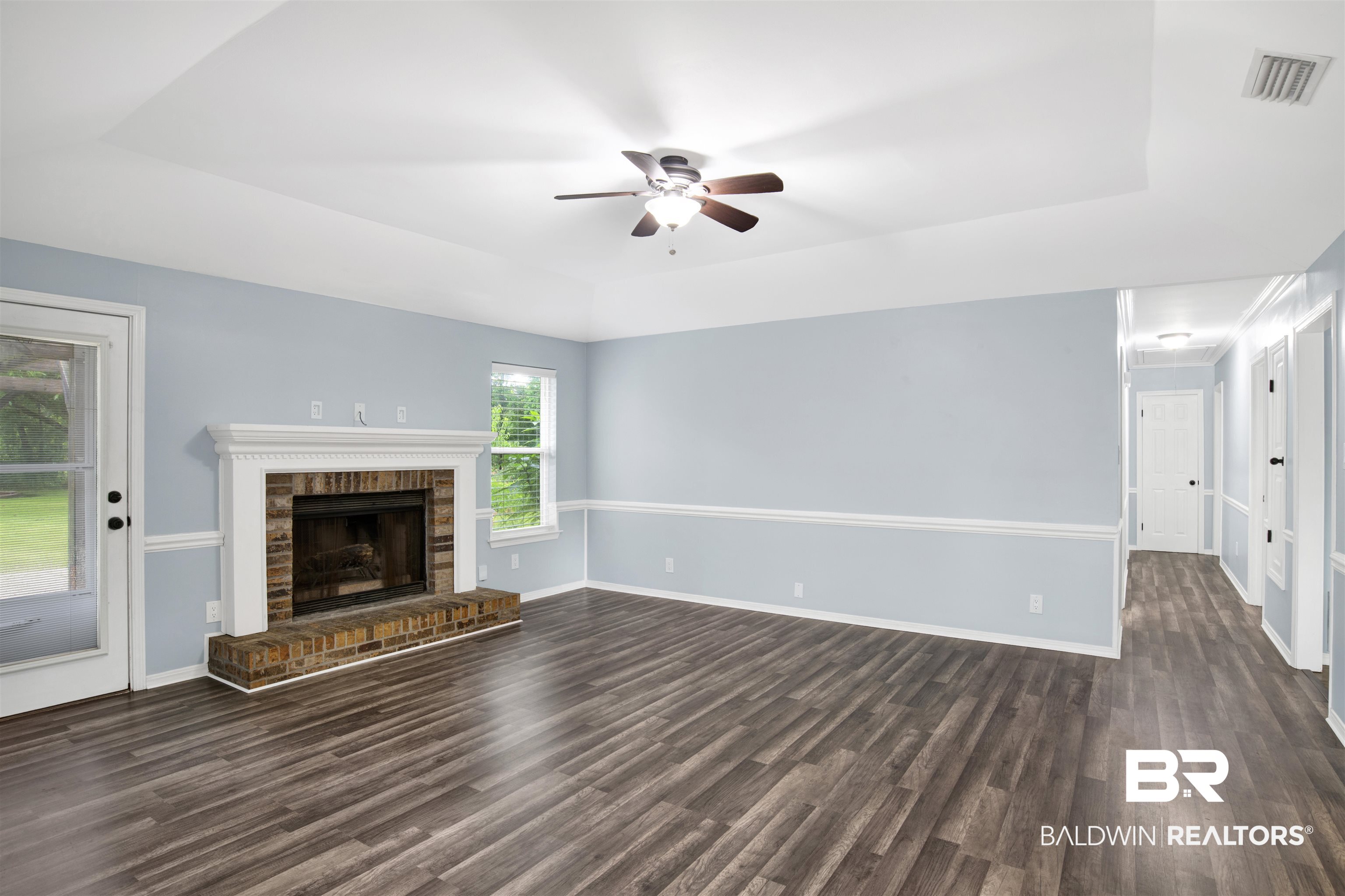 3011 Olde Gate Road Mobile, AL 36695 - Photo 9 of 35 Unfurnished living room featuring a raised ceiling, dark wood-style flooring, ceiling fan, and a fireplace