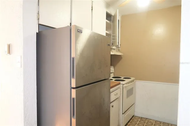 a view of a kitchen with refrigerator and white wall