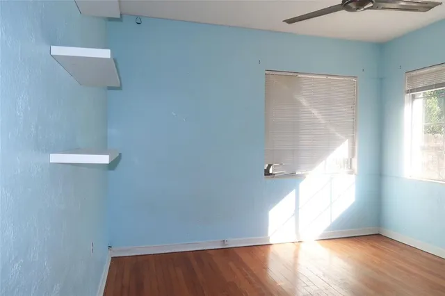 a view of empty room with wooden floor and fan
