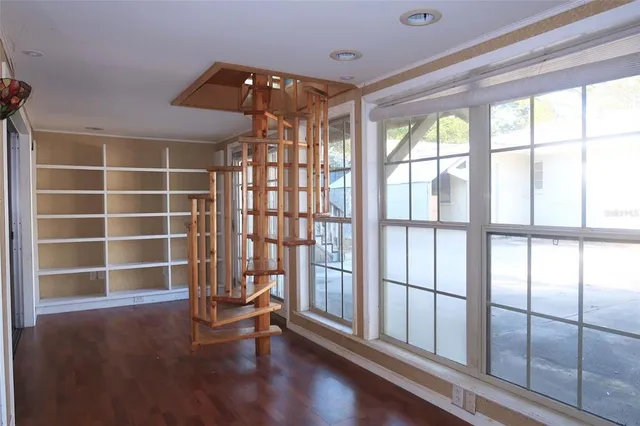 a view of an empty room with a window and wooden floor