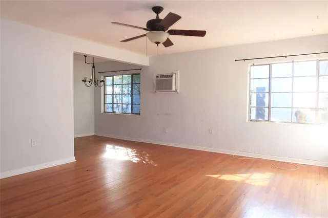 a view of an empty room with window and wooden floor