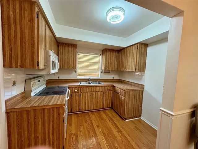 a kitchen with a sink a stove cabinets and wooden floor