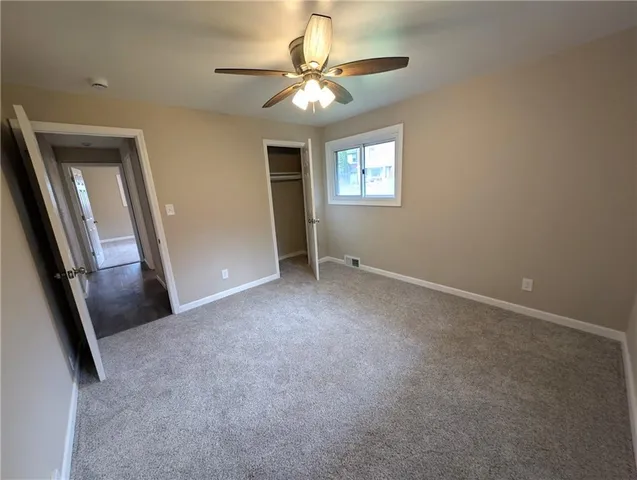 a view of a livingroom with a chandelier fan and windows