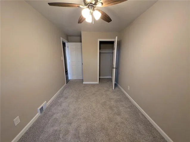 an empty room with a chandelier fan and windows
