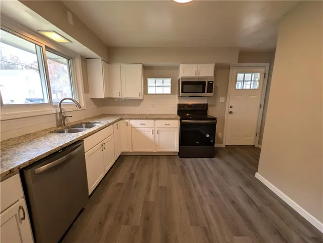 a kitchen with granite countertop a refrigerator sink and wooden cabinets