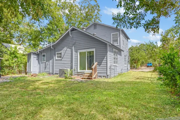 a front view of house with yard and trees in the background