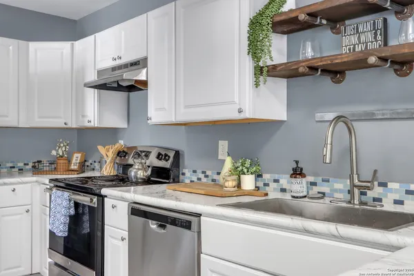 a kitchen with stainless steel appliances granite countertop a sink a stove and cabinets