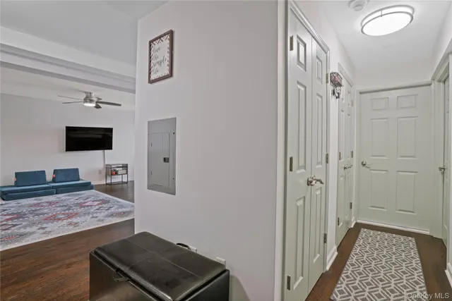 a view of a hallway to room with wooden floor and flat screen tv