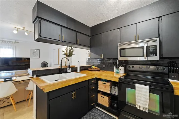 a kitchen with stainless steel appliances kitchen island granite countertop a refrigerator a stove and a sink with wooden floor