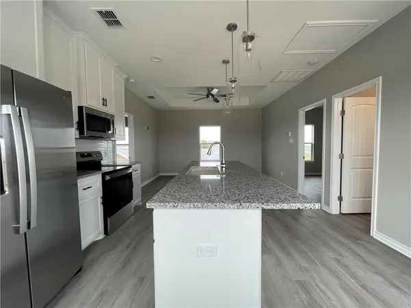 a kitchen with stainless steel appliances granite countertop a refrigerator a sink dishwasher a stove and a refrigerator with wooden floor