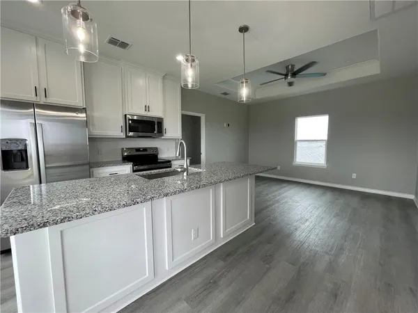 a kitchen with stainless steel appliances granite countertop a sink a stove a refrigerator a center island with wooden floor