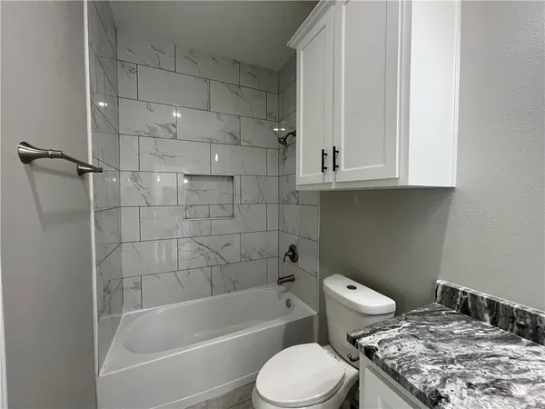 a bathroom with a granite countertop toilet a sink and bathtub