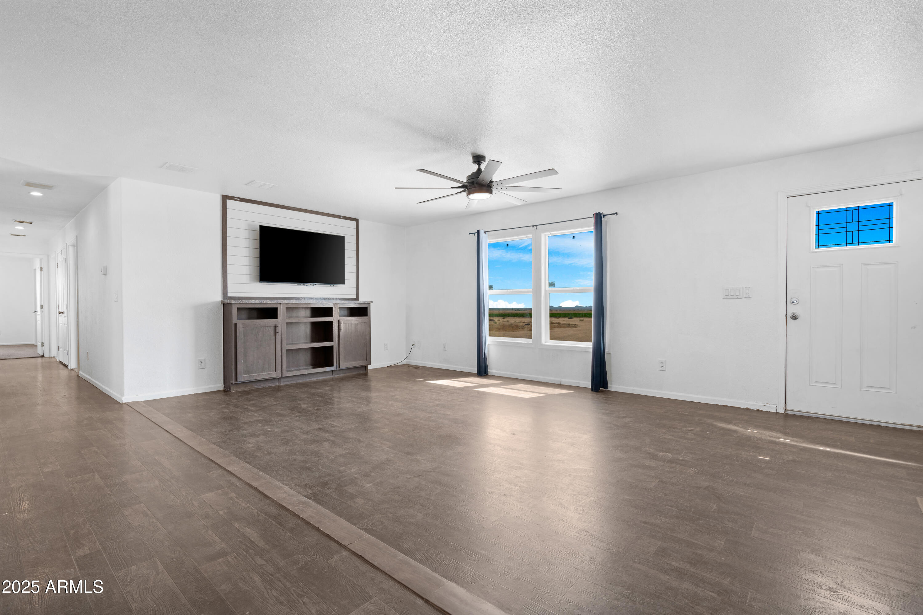4318 North White Road Maricopa, AZ 85139 - Photo 4 of 21 a view of a livingroom with a flat screen tv wooden floor and a ceiling fan