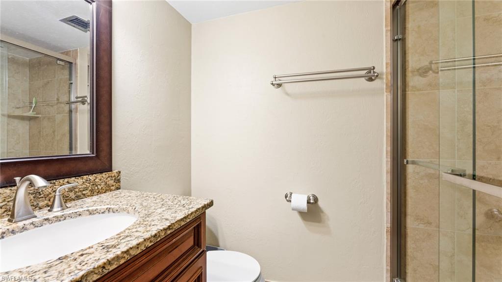 45 High Point Circle South, Unit 304 Naples, FL 34103 - Photo 14 of 20 a bathroom with a granite countertop sink toilet and shower