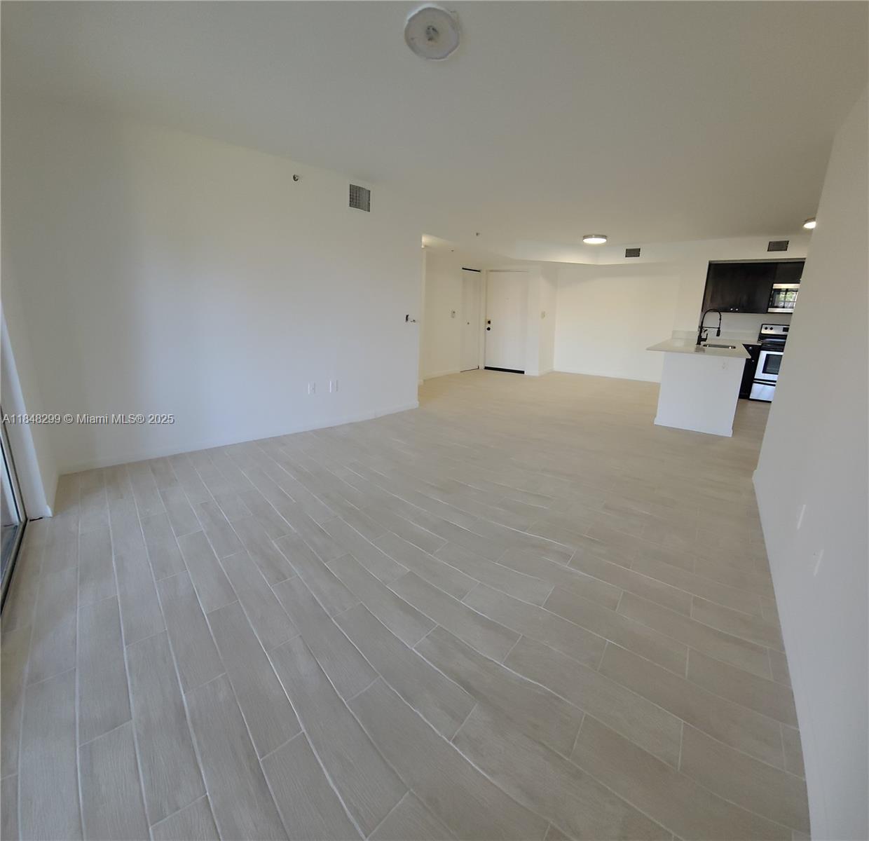 2021 Renaissance Boulevard, Unit 104 Miramar, FL 33025 - Photo 5 of 16 an empty room with wooden floor and windows