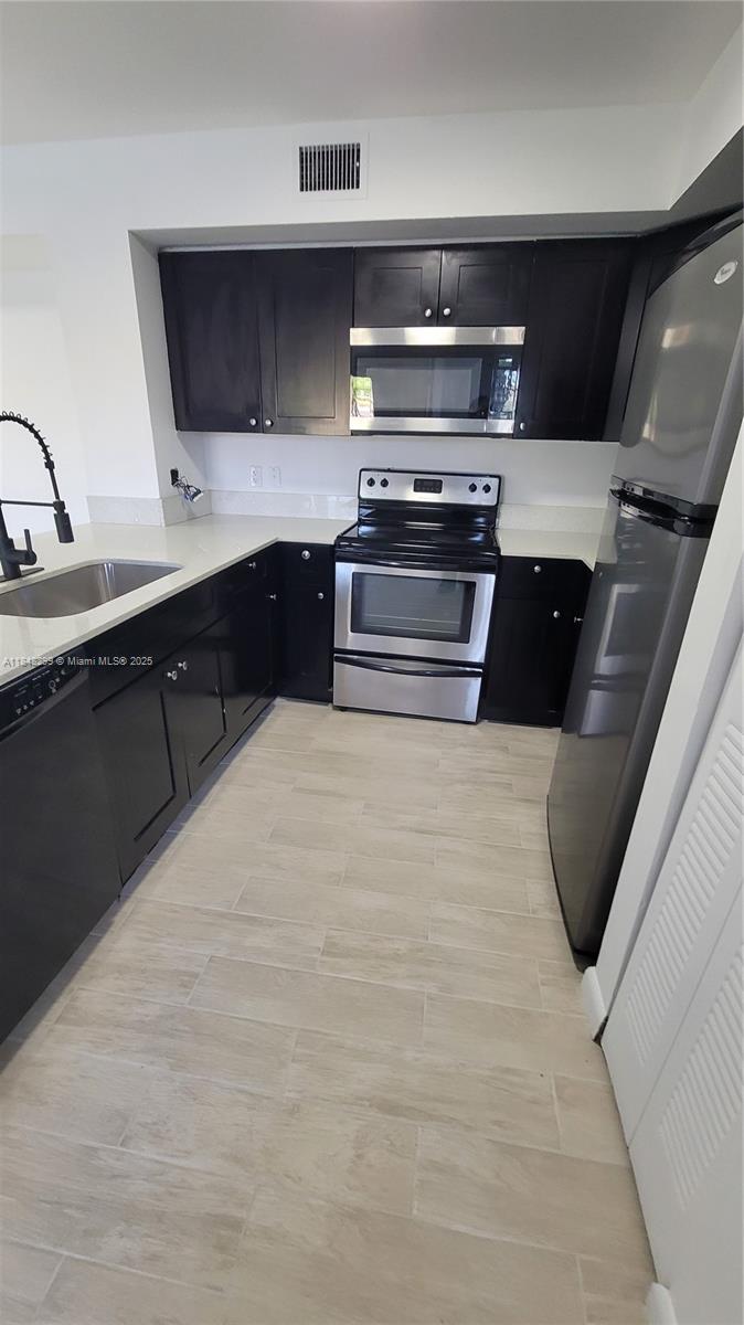 2021 Renaissance Boulevard, Unit 104 Miramar, FL 33025 - Photo 6 of 16 a kitchen with stainless steel appliances a sink and a stove