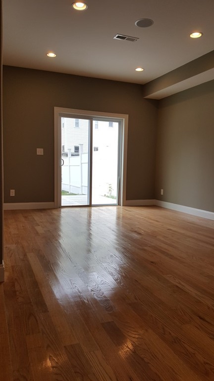 25 Robey Street, Unit 25 Boston, MA 02119 - Photo 6 of 13 an empty room with wooden floor and windows