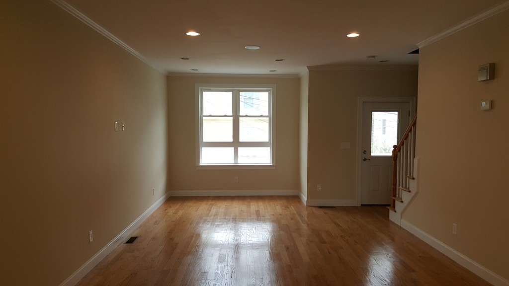 25 Robey Street, Unit 25 Boston, MA 02119 - Photo 7 of 13 an empty room with wooden floor and windows