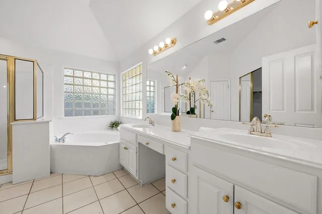 a spacious bathroom with a double vanity sink mirror and bathtub