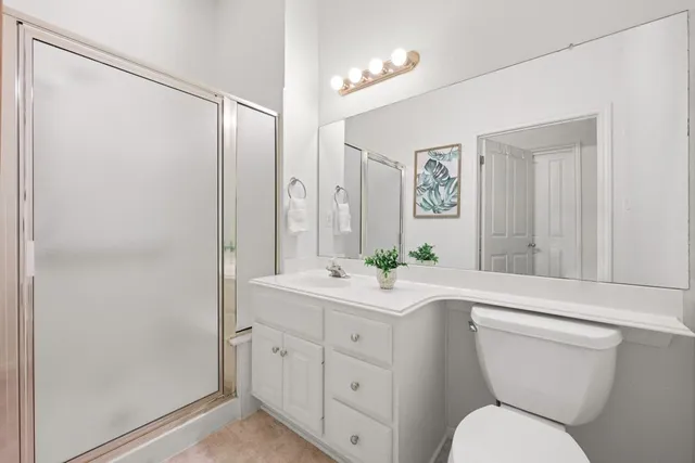 a bathroom with a toilet a sink a mirror a shower and vanity