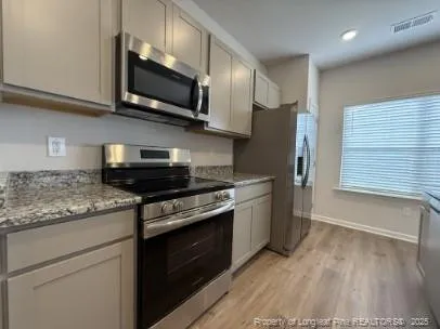 a kitchen with stainless steel appliances granite countertop a stove a microwave and a refrigerator