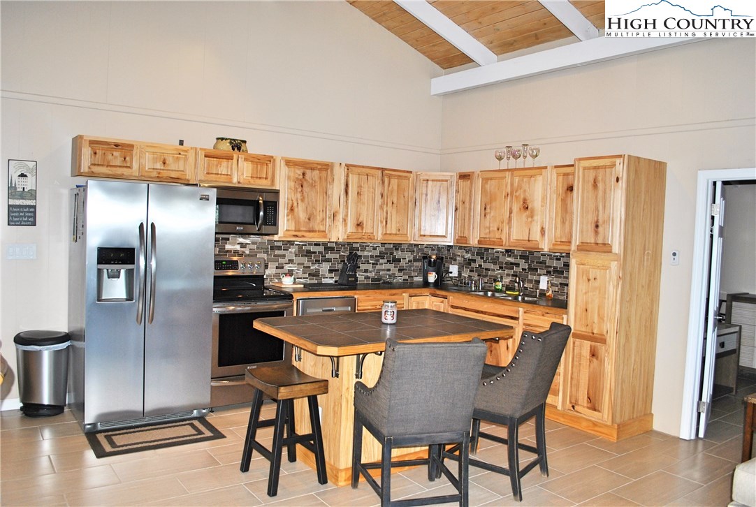 104 Pine Ridge Road Beech Mountain, NC 28604 - Photo 9 of 25 a kitchen with stainless steel appliances granite countertop a dining table chairs and refrigerator