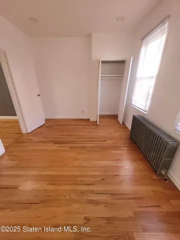 a view of an empty room with wooden floor and windows