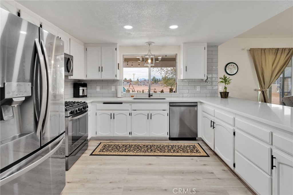 21291 Ramona Road Apple Valley, CA 92307 - Photo 14 of 35 a kitchen with a refrigerator sink and cabinets