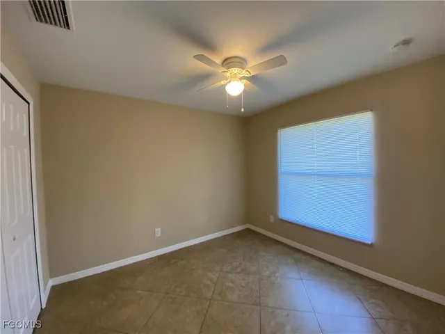 an empty room with windows and fan