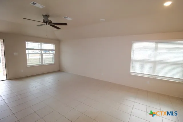 an empty room with windows and ceiling fan