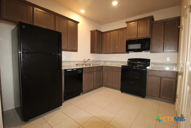 a kitchen with a sink a refrigerator and cabinets