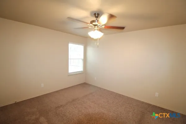 an empty room with a window and a fan