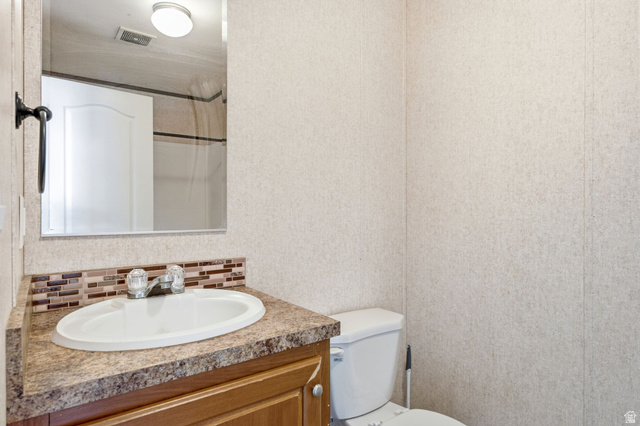 2875 North Hill Field Road, Unit 62 Layton, UT 84041 - Photo 20 of 34 Bathroom vanity featuring a white oval sink, chrome faucet, and a brown patterned countertop with a mosaic tile backsplash