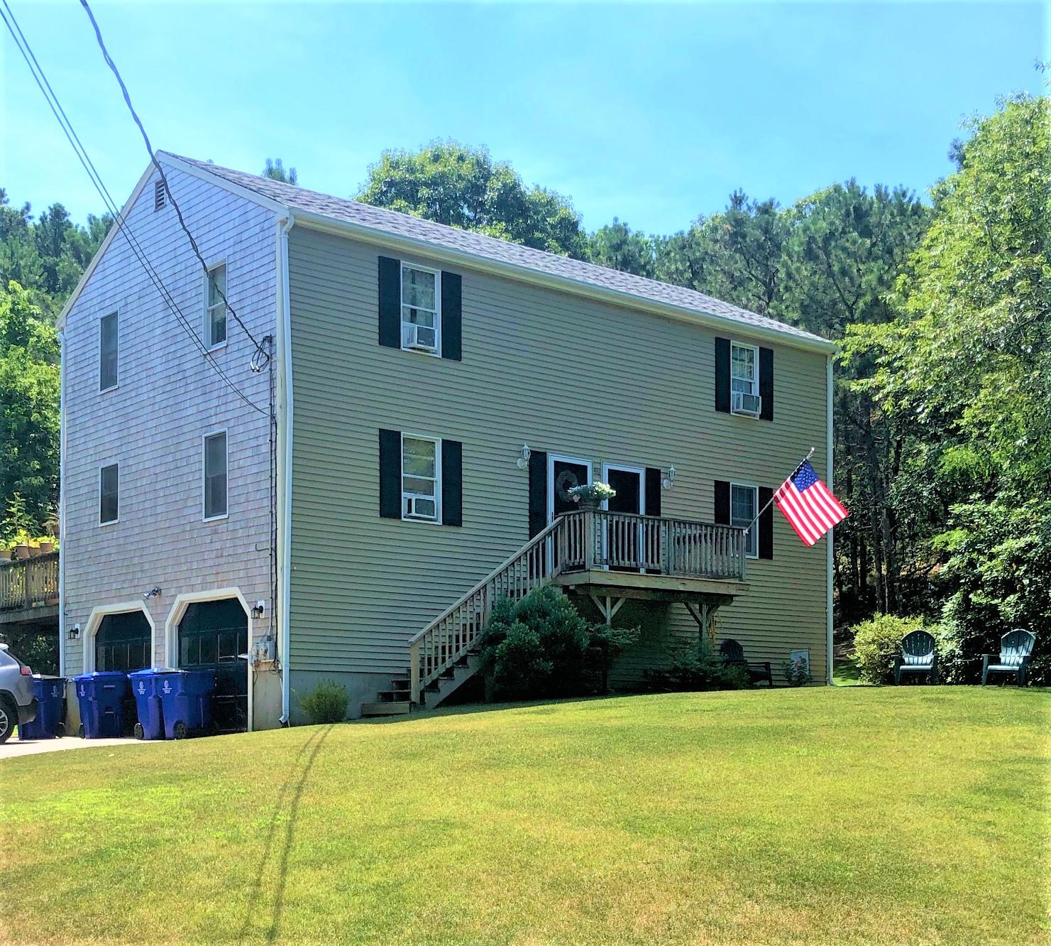 a front view of house with yard and trees in the background