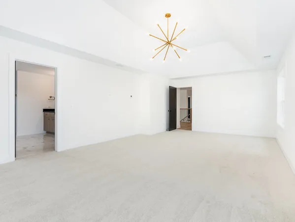 an empty room with a chandelier fan and windows