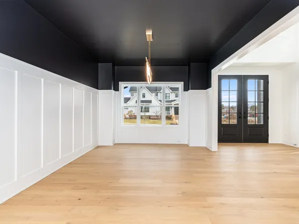 a view of a refrigerator in kitchen and an empty room with wooden floor