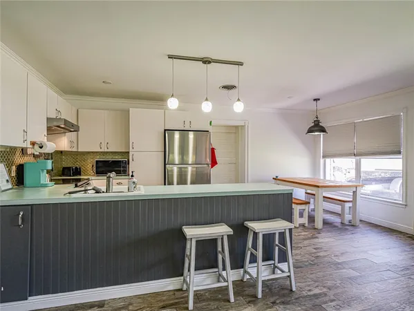 a kitchen with kitchen island granite countertop a table chairs sink and cabinets